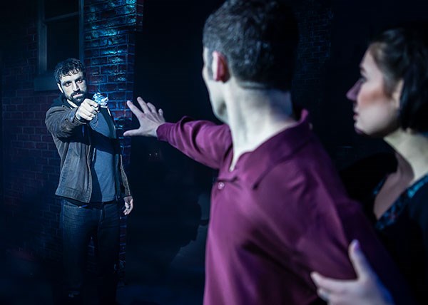 Ghost the Musical man reaching out to protect a woman, whilst another man points a gun